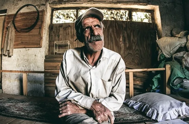 An old man in a cap sitting in his workshop